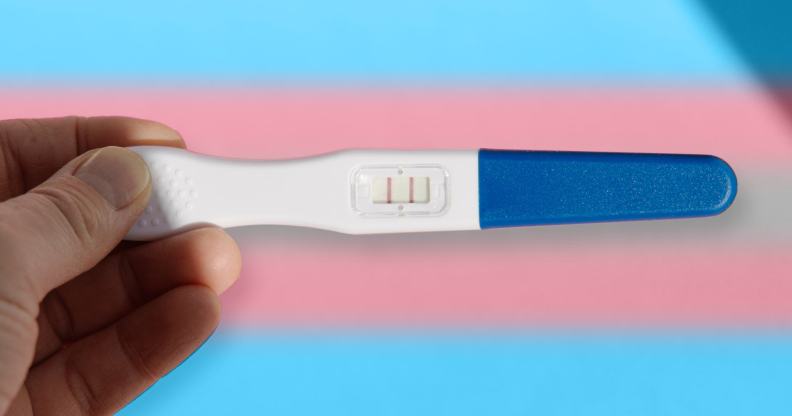 pessoa segurando um teste de gravidez sobre as cores da bandeira trans